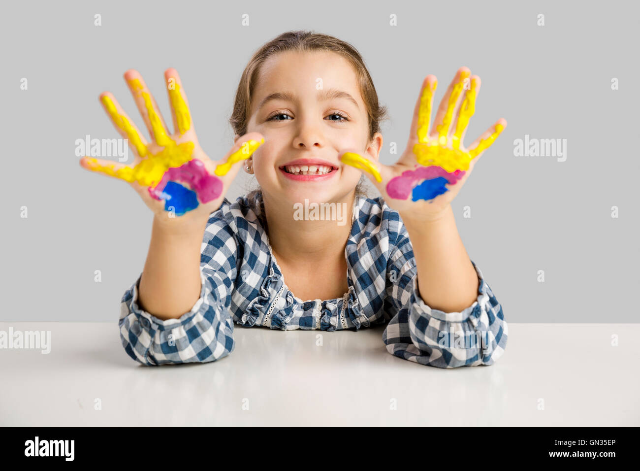 Cute smiling little girl avec les mains dans la peinture Banque D'Images