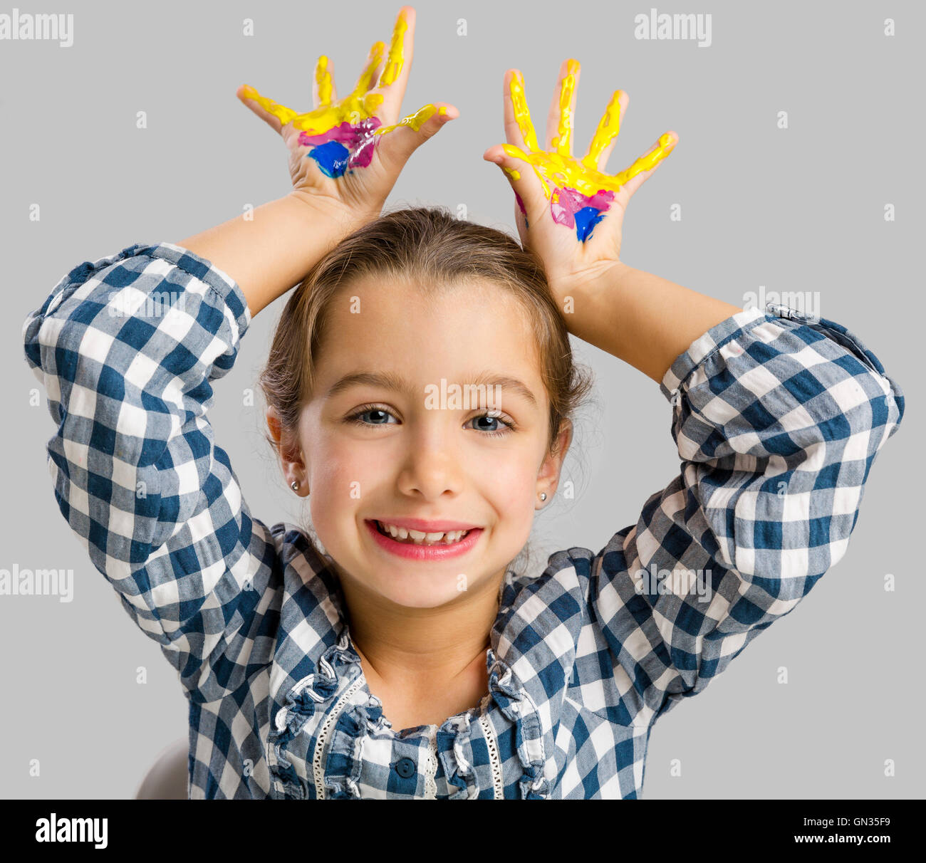 Cute smiling little girl avec les mains dans la peinture Banque D'Images