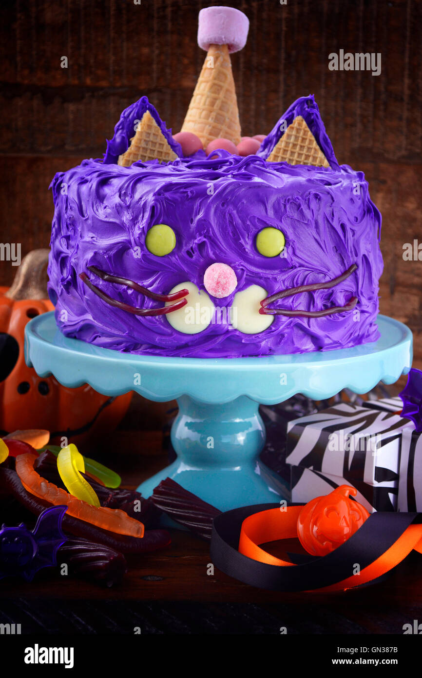 Happy Halloween cat gâteau partie nourriture avec glaçage violet candy et décorations sur fond en bois sombre. Banque D'Images