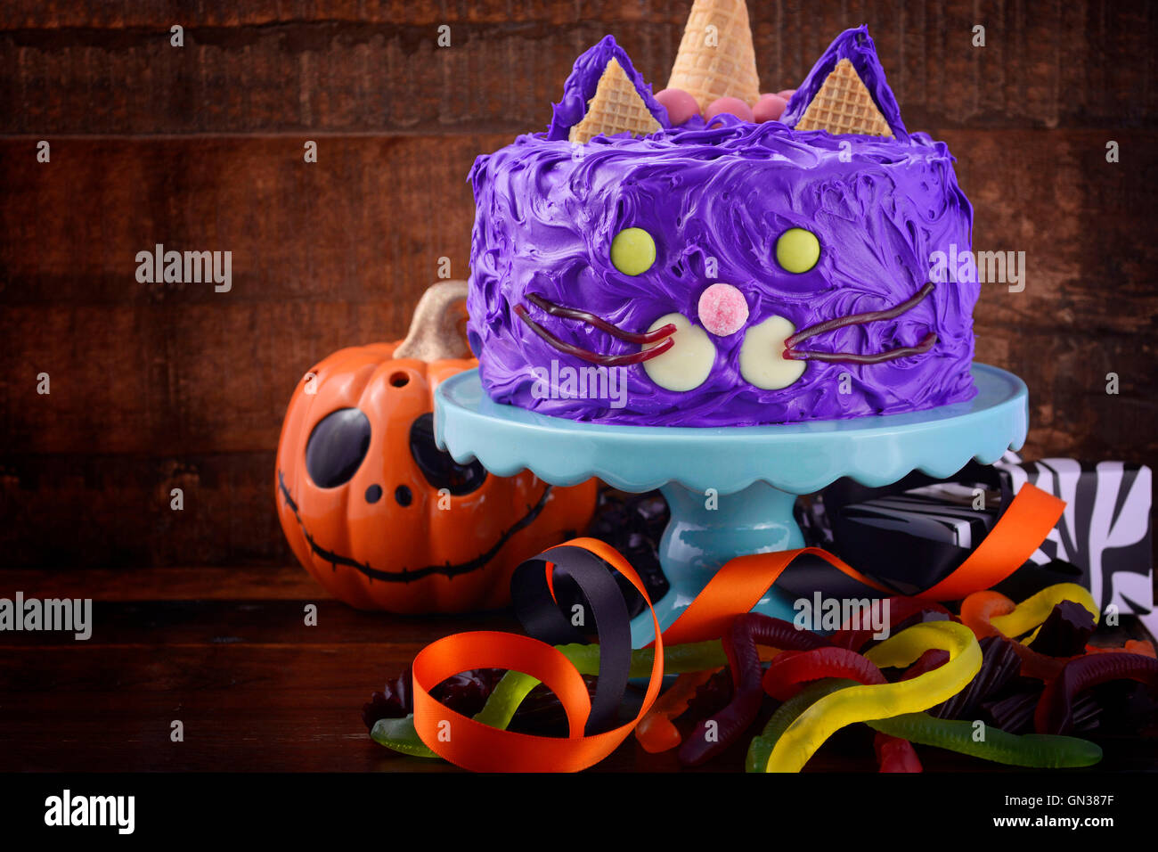 Happy Halloween cat gâteau partie nourriture avec glaçage violet candy et décorations sur fond en bois sombre. Banque D'Images