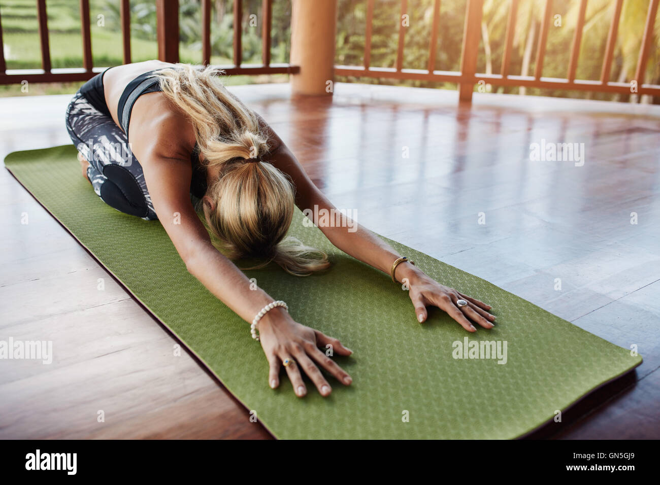 Young woman doing stretching entraînement sur tapis de fitness. Yoga féminin sur tapis d'exercice à la salle de sport. Pose de l'enfant, Balasana. Banque D'Images
