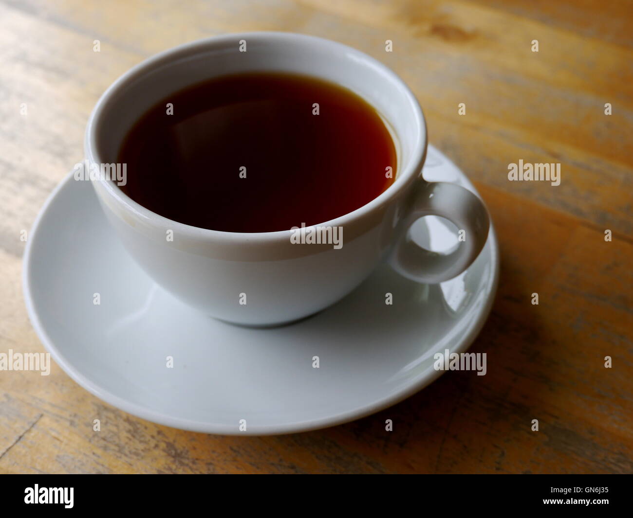 Tasse de café noir sur une table en bois Banque D'Images