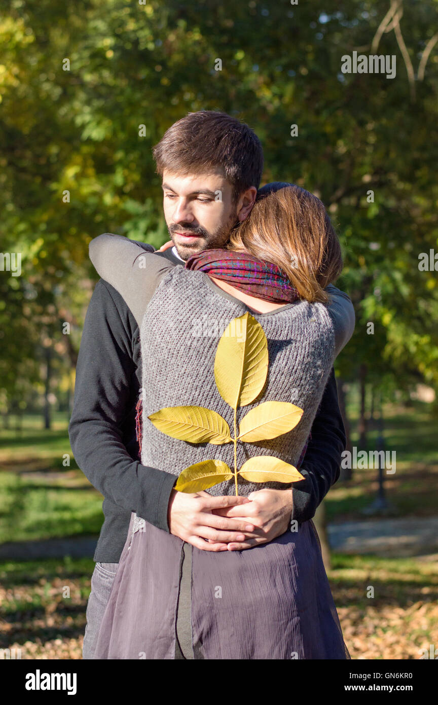 Loving couple hugging dans le parc tout en maintenant les feuilles d'automne jaune Banque D'Images