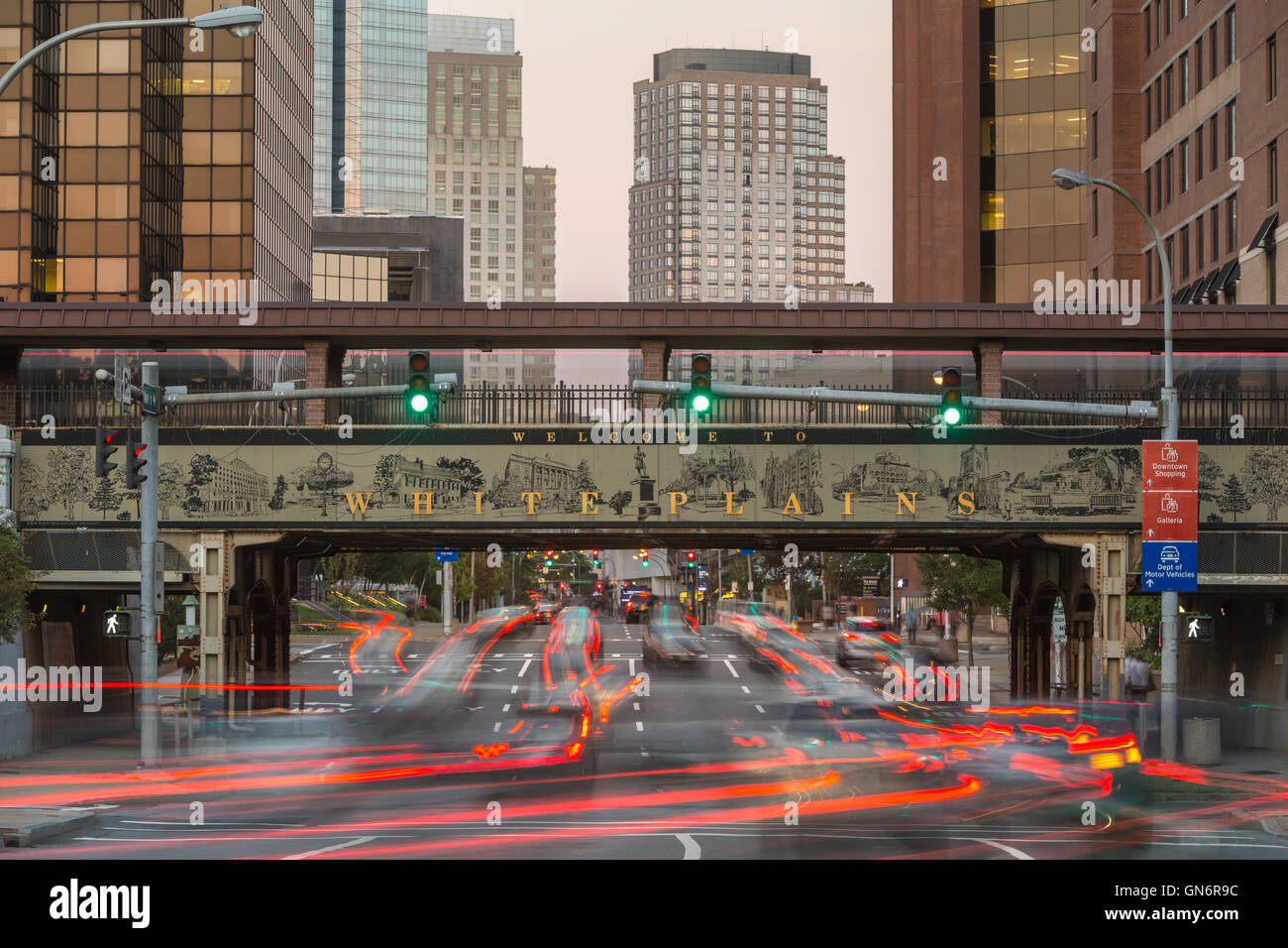 Des sentiers de lumière crée du trafic sous le panneau de bienvenue sur le viaduc de la Tunisie) entrant dans le centre-ville de White Plains, New York. Banque D'Images