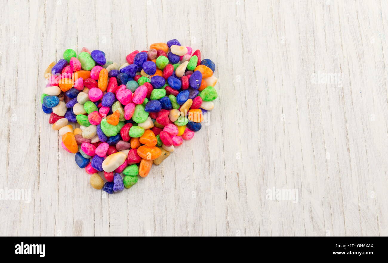 Les roches colorées formant une forme de coeur sur table en bois Banque D'Images