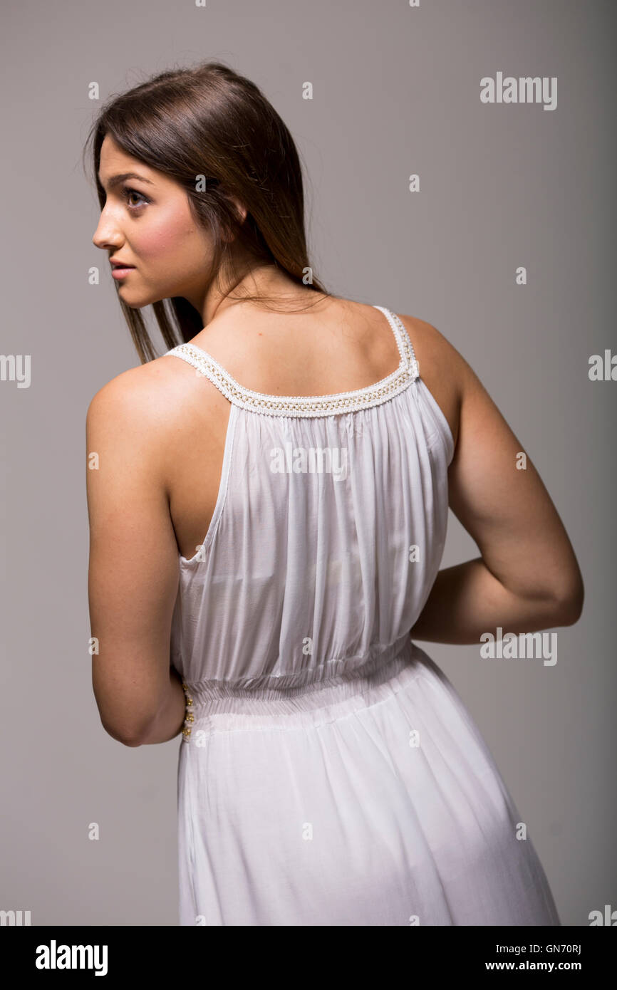 Jolie jeune femme aux cheveux longs en robe blanche en studio Banque D'Images