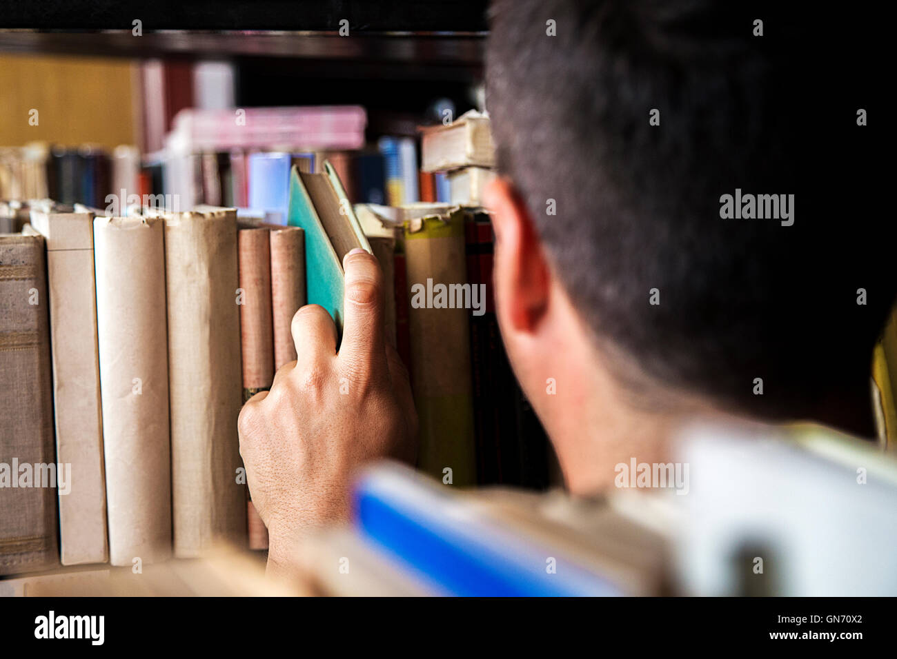 Jeune homme de choisir un livre dans la bibliothèque Banque D'Images