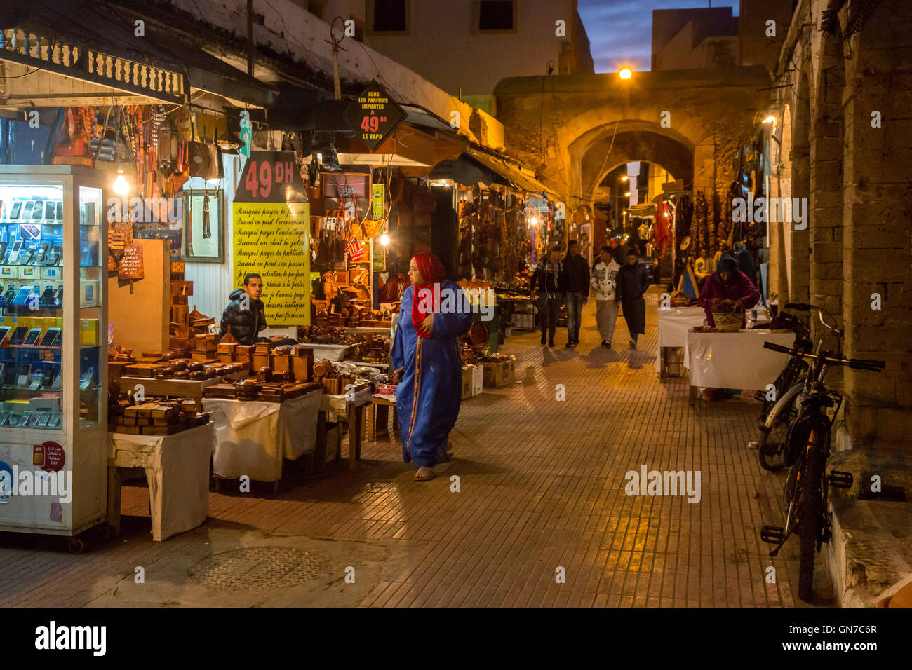 Essaouira, Maroc. Scène de rue le soir, les boutiques de téléphones cellulaires et de souvenirs en bois de thuya. Banque D'Images