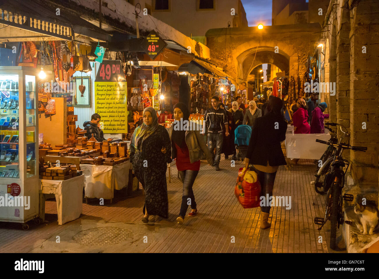 Essaouira, Maroc. Scène de rue le soir, les boutiques de téléphones cellulaires et de souvenirs en bois de thuya. Banque D'Images