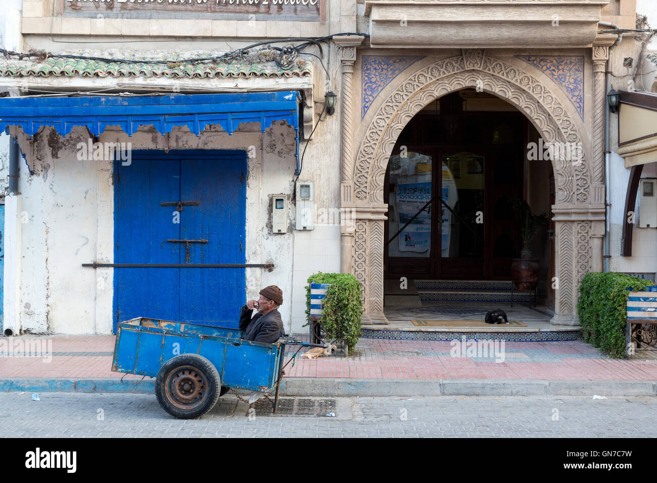 Essaouira, Maroc. A porter avec son deux-roues panier attend dans la médina pour un client dans le besoin. Banque D'Images