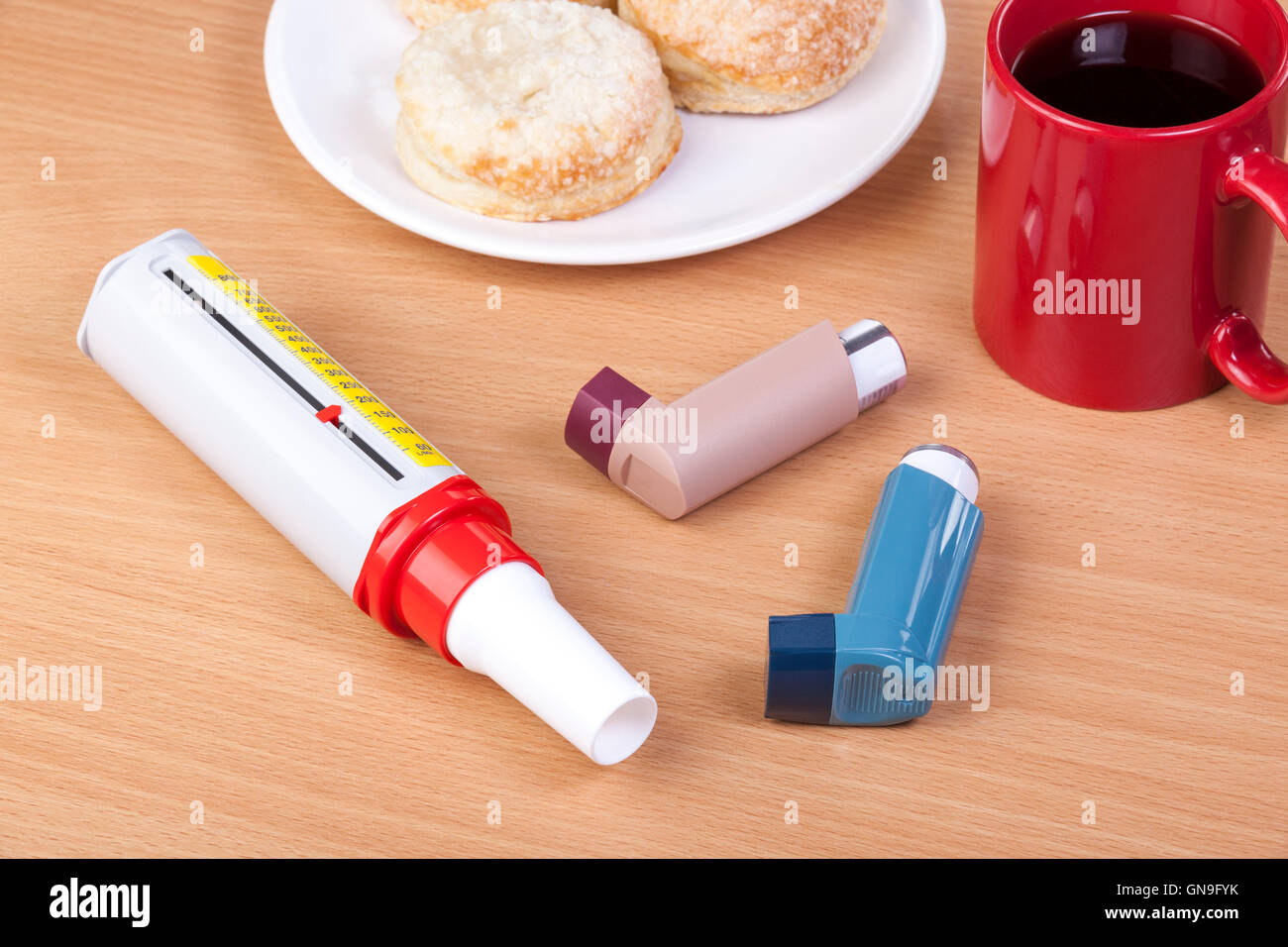 Bleu et marron l'asthme inhalateurs spray fixant sur une table de petit déjeuner avec un débitmètre peek à côté d'une tasse de café noir et un plat Banque D'Images