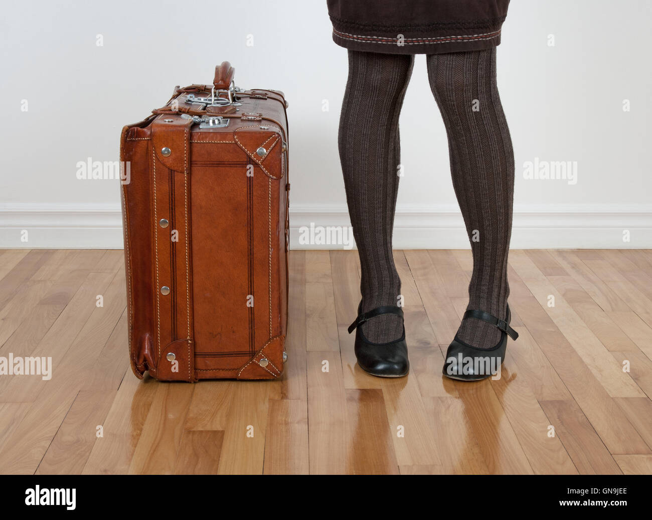 Femme en bas brun debout près de vintage suitcase Banque D'Images