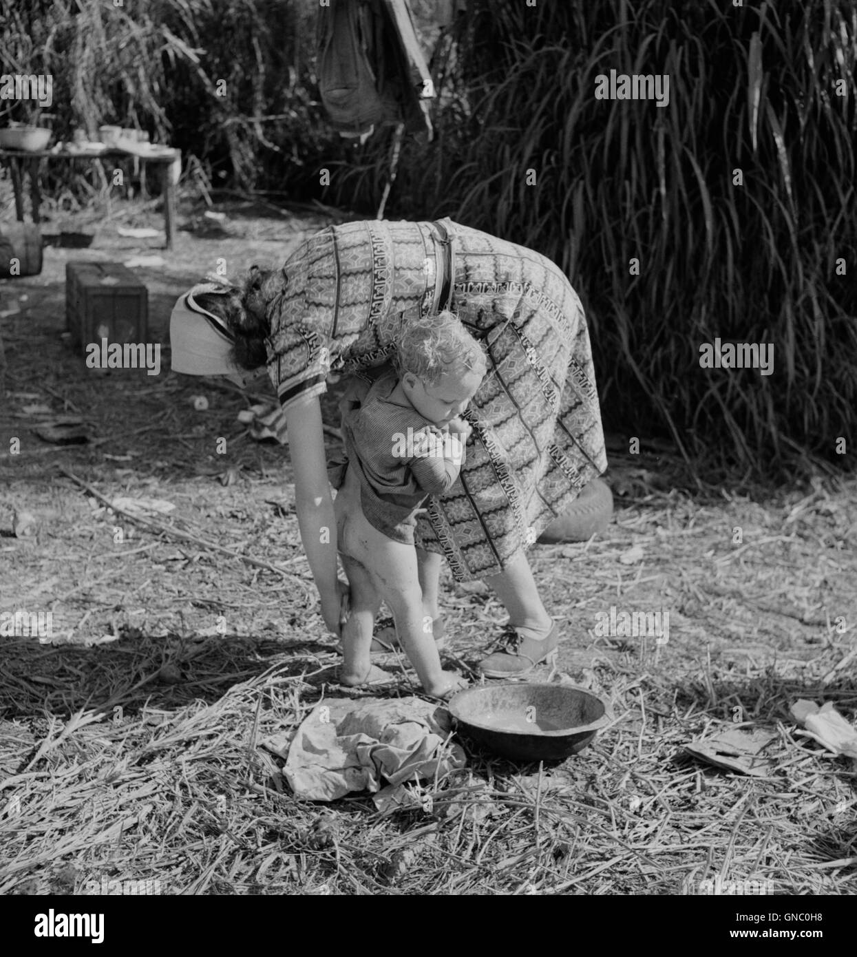 Femme d'emballage Nettoyage travailleur son jeune enfant avec l'eau sale du canal voisin, Belle Glade en Floride, USA, Marion Post Wolcott pour Farm Security Administration, Banque D'Images