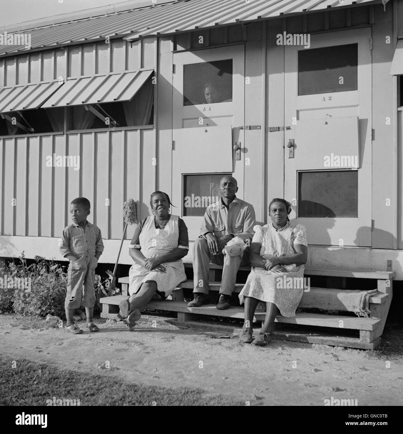 Famille de travailleurs migrateurs assis devant leur abri métallique, camp de travail migratoire d'Okeechobee, Belle Glade, Floride, États-Unis, Marion Post Wolcott, ÉTATS-UNIS Administration de la sécurité agricole, février 1941 Banque D'Images