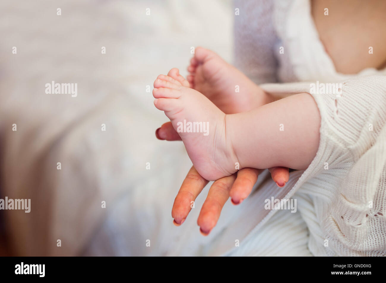 Mother holding little baby's feet on bed Banque D'Images