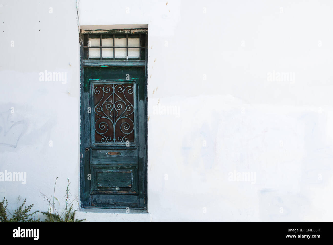 Vieille porte bleue avec grille d'ornement. La façade blanche de la chambre. Quelques plantes dans le coin. Quartier du Plaka à Athènes, Grèce. Banque D'Images