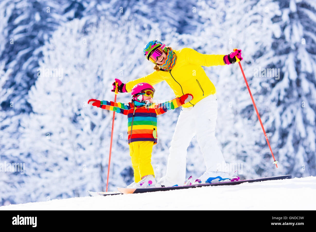La mère et le petit enfant du ski dans les montagnes des Alpes. Maman active et tout-petit enfant avec casque de sécurité, lunettes et des poteaux. Banque D'Images