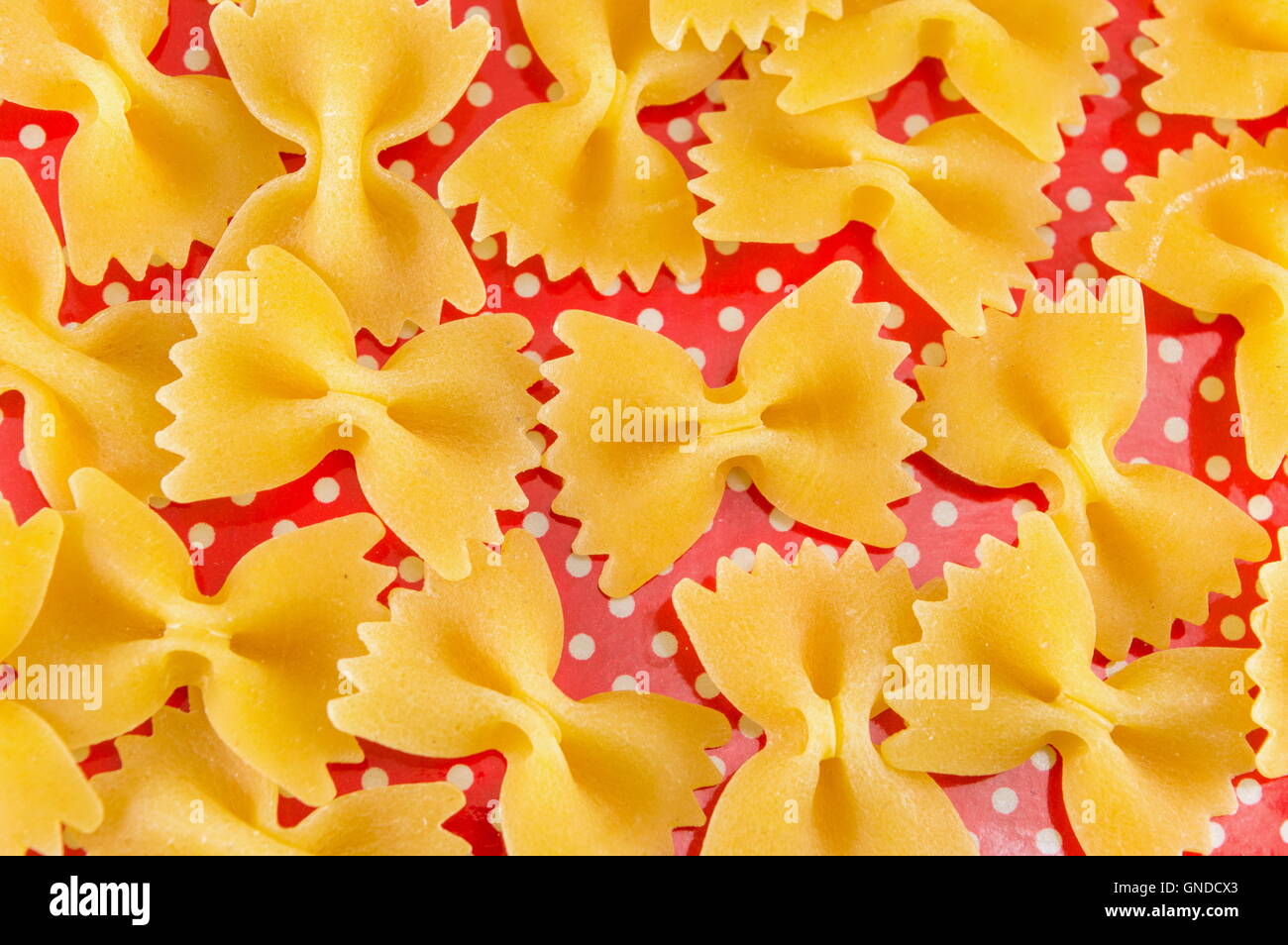Pâtes farfalle papillon non cuites sur red dotted background Banque D'Images