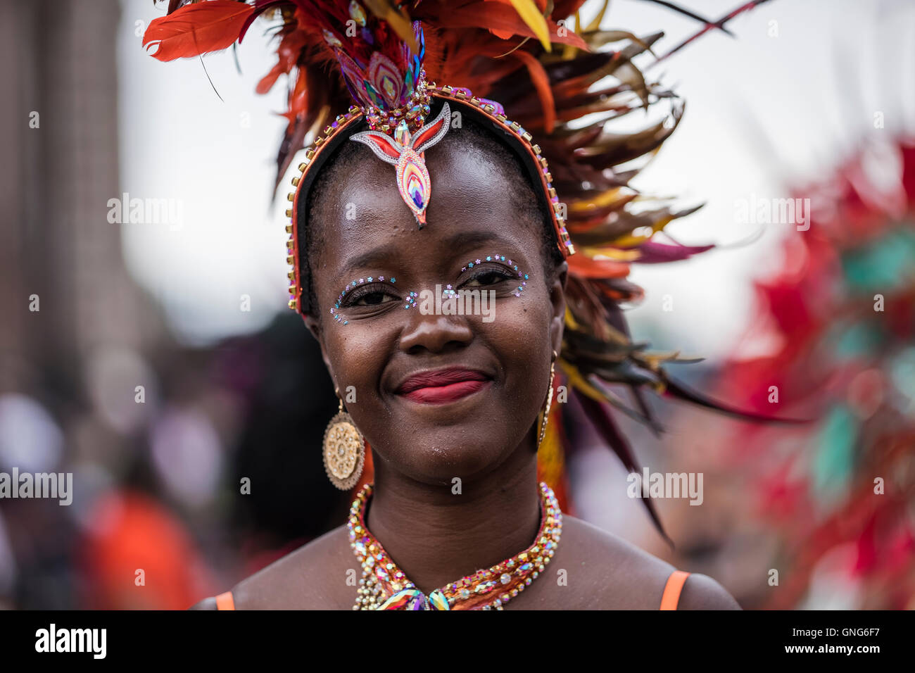Belle dame noire avec le rouge à lèvres rouge et merveilleux à la coiffure de plumes du carnaval de Notting Hill dans l'ouest de Londres Banque D'Images