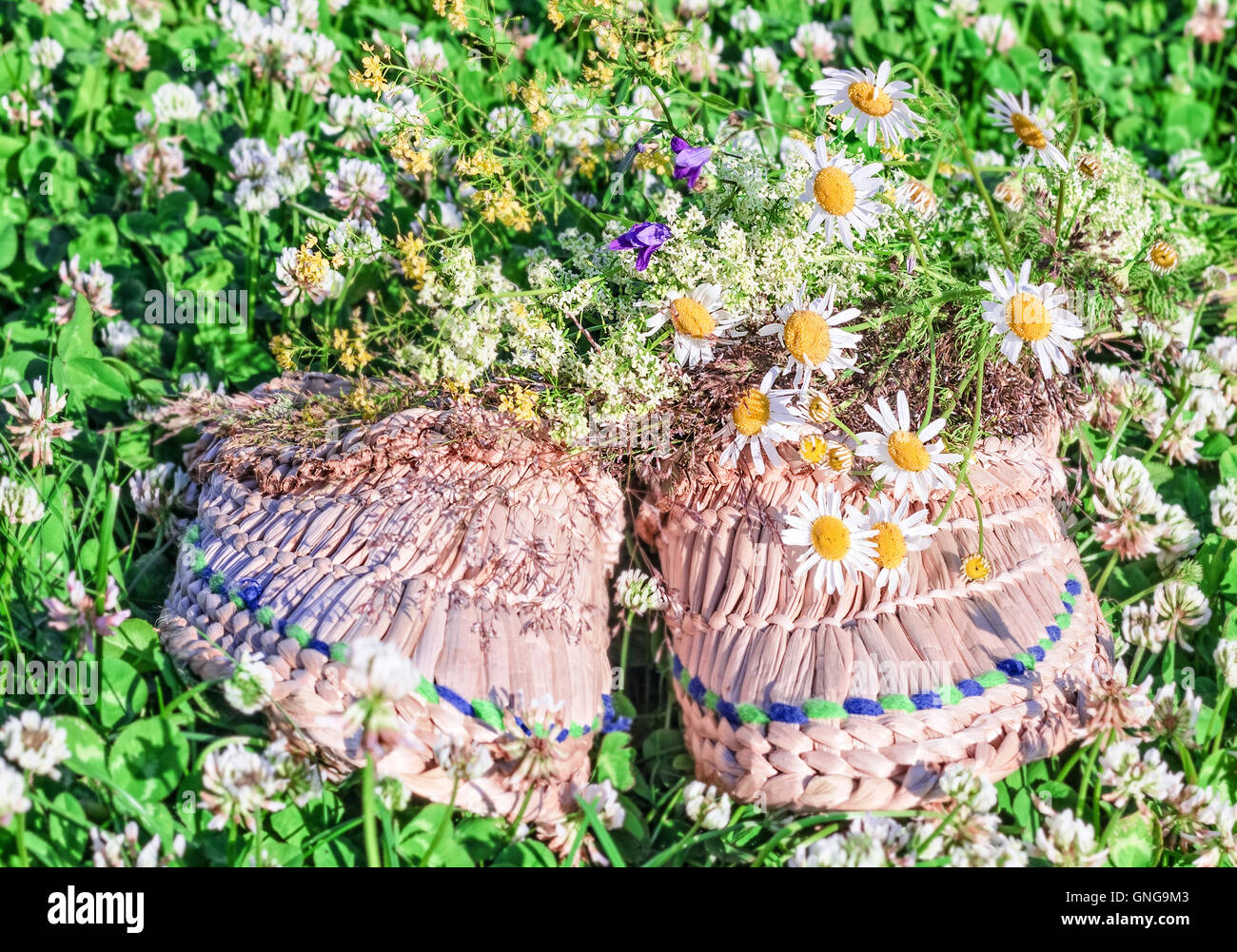 Tissé de paille chaussons en herbe l'été et de bouquet de fleurs sur le terrain Banque D'Images