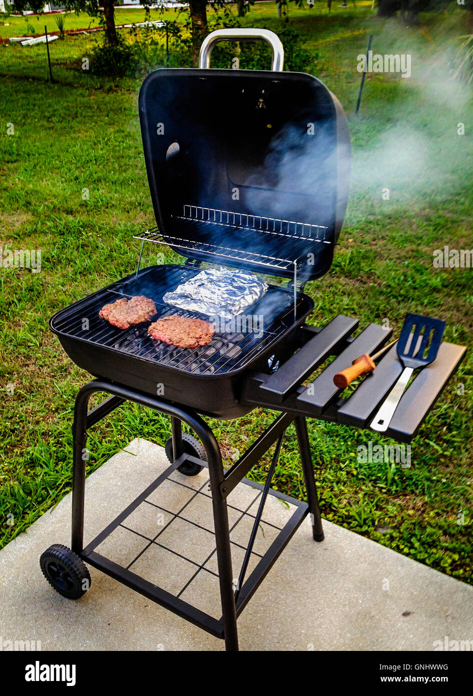Jardin Barbecue la cuisson des hamburgers et des haricots enveloppés  d'aluminium Photo Stock - Alamy