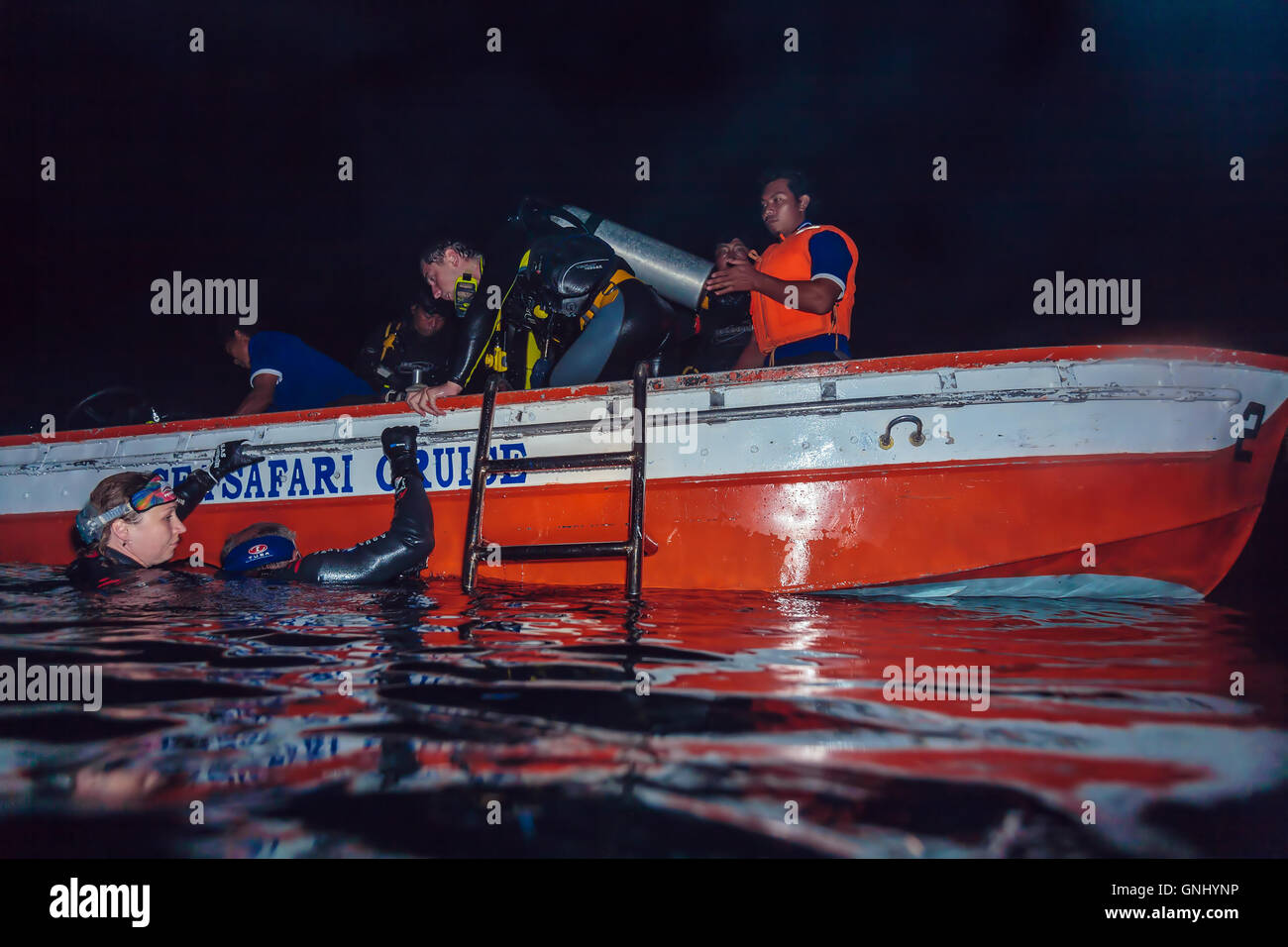 L'ÎLE DE BALI, INDONÉSIE - août 21, 2008 : Groupe de plongeurs escalade à petit bateau après la plongée de nuit Banque D'Images
