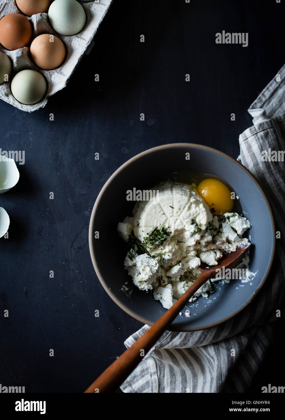 Fromage à la ricotta dans un bol avec les oeufs et les herbes. Banque D'Images