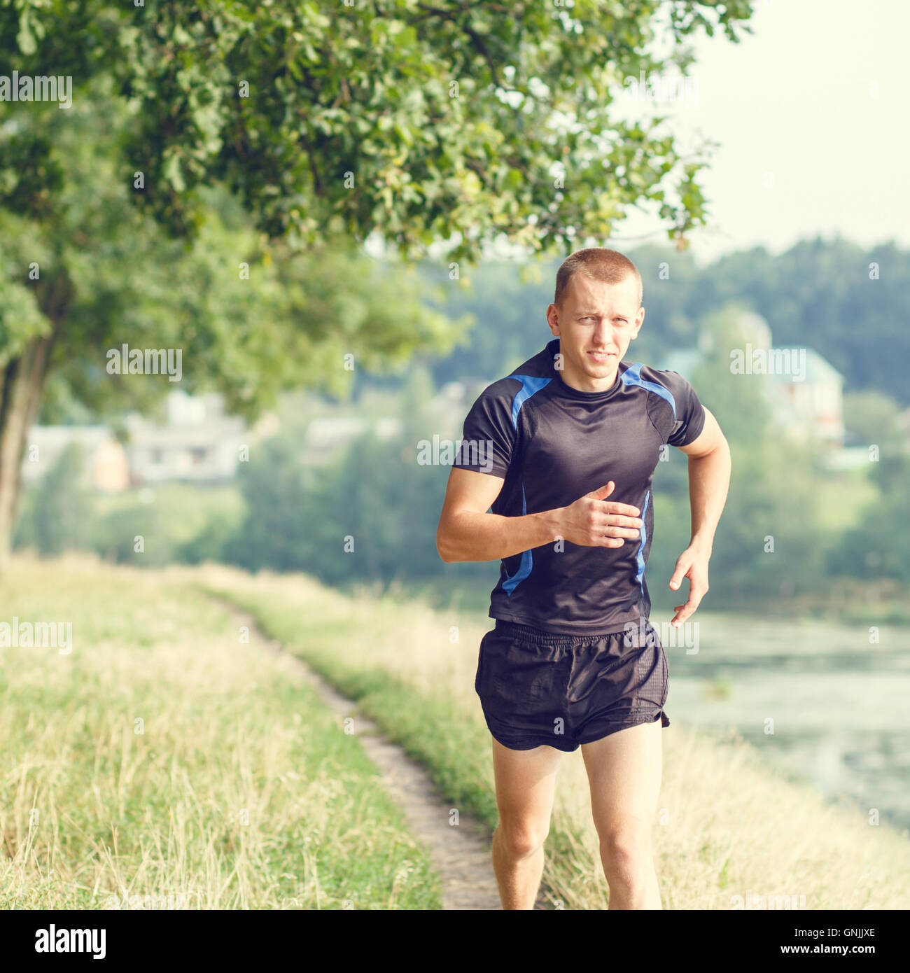 Jeune homme athlétique jogging en matin parc. La formation en cours d'exécution en plein air avec copie espace Banque D'Images