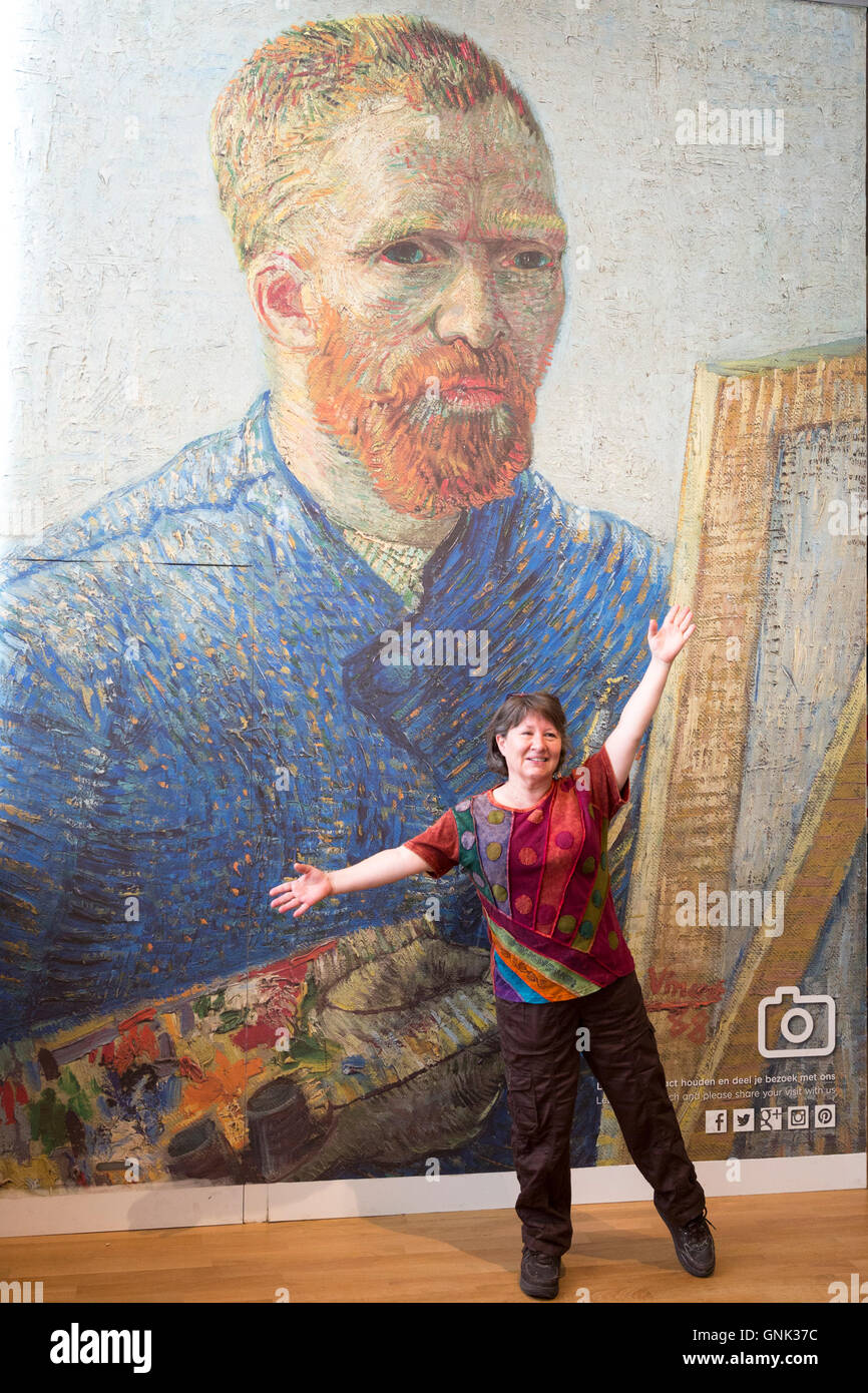 Woman posing in front of poster d'autoportrait de Vincent Van Gogh au Musée Van Gogh à Amsterdam, Hollande galerie Banque D'Images