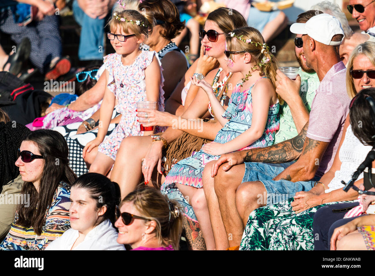 Festival de la semaine folklorique de Broadstairs. Vue latérale d'un public assis à l'extérieur dans le soleil, jeune mère de deux filles avec des fleurs dans leurs cheveux. Banque D'Images