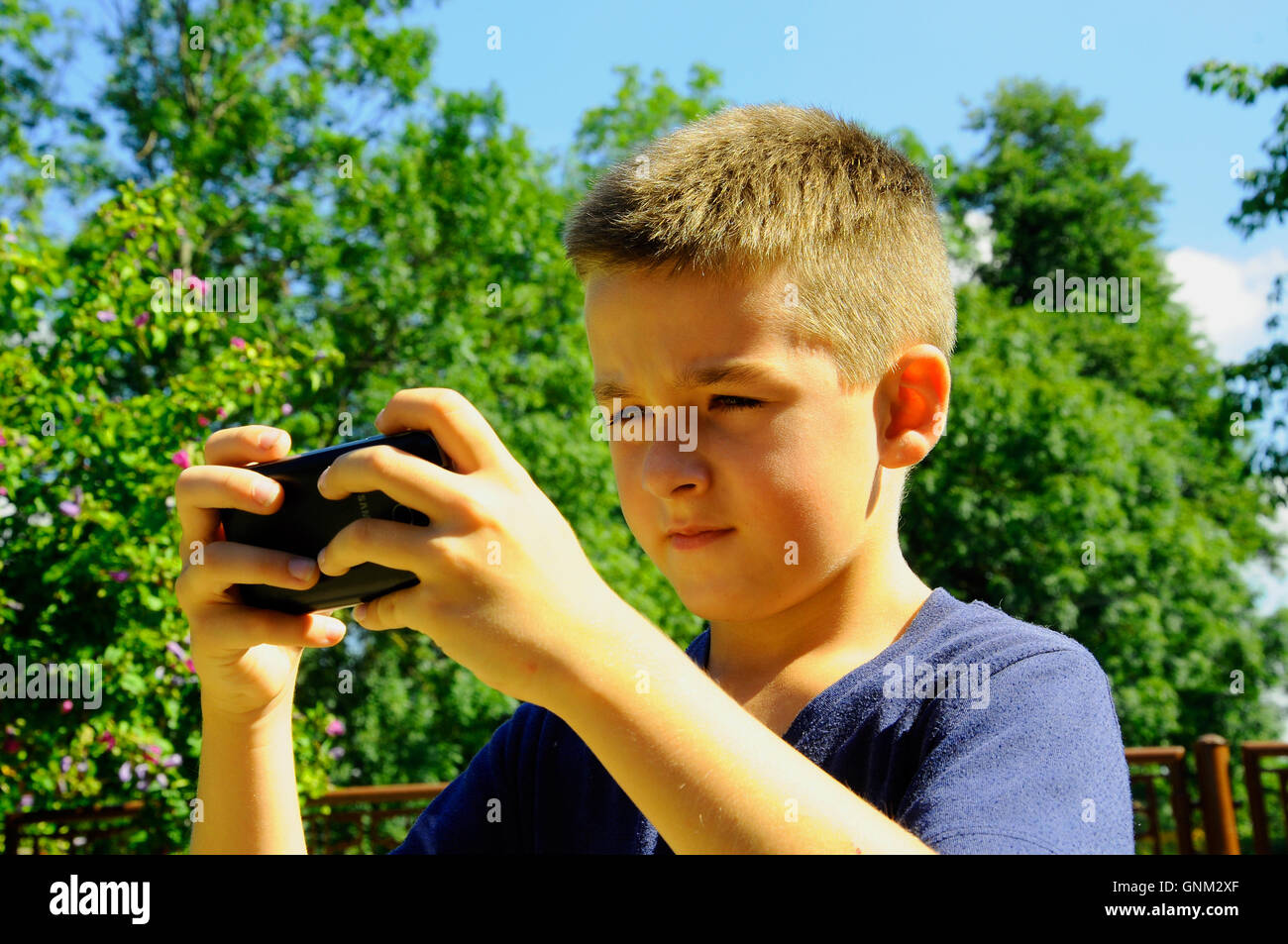 Jeune garçon en vacances avec ma grand-mère dans le village de jouer avec un nouveau téléphone mobile games Banque D'Images