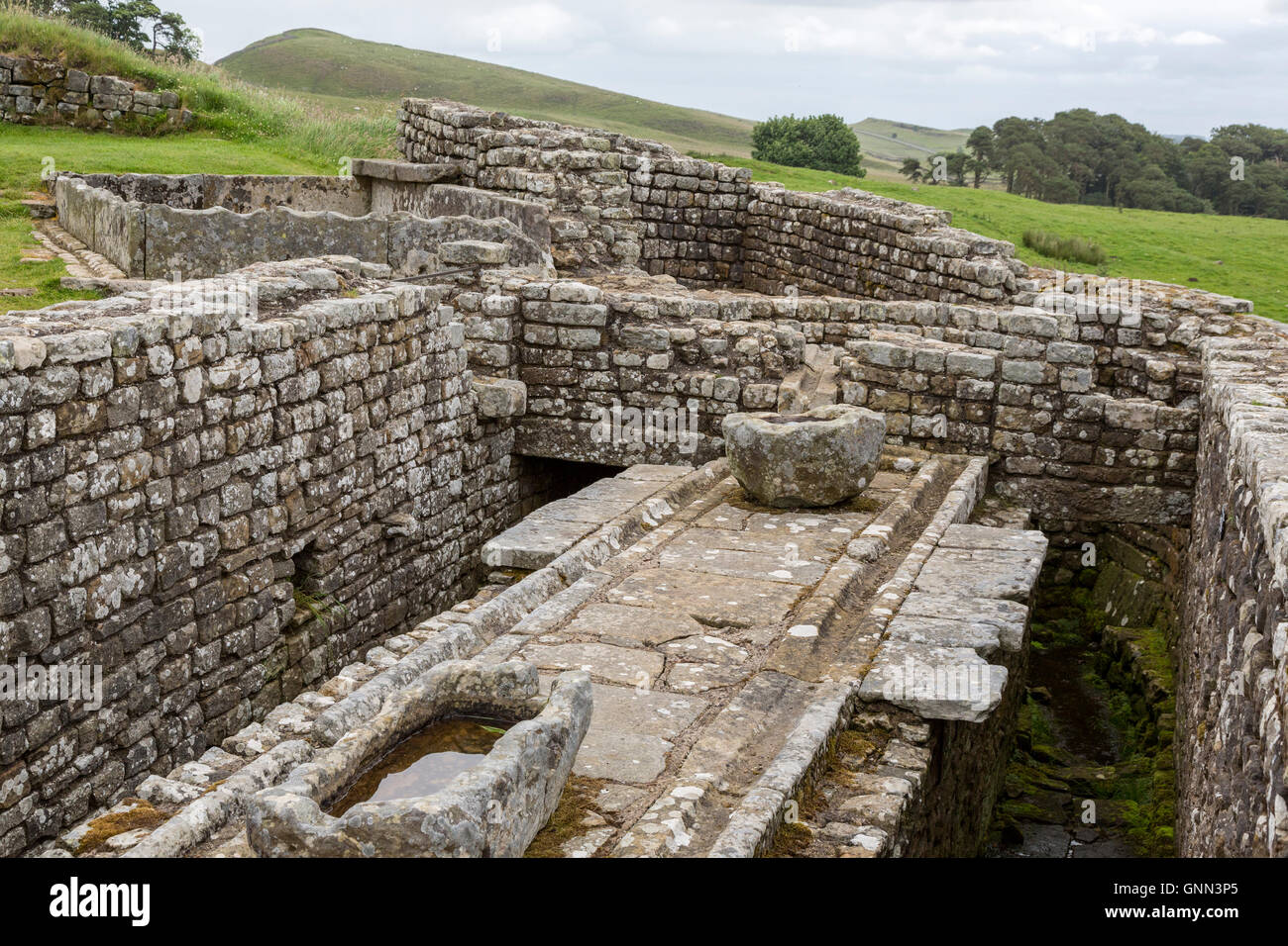 Northumberland, England, UK. Les latrines, Fort romain de Housesteads (Vercovicium). Citerne d'eau sur la gauche. Banque D'Images