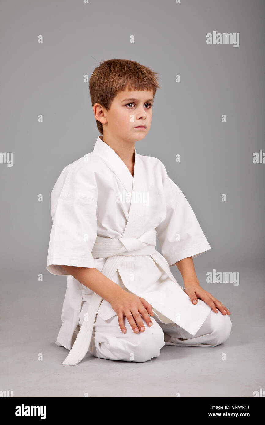 Karate boy en kimono blanc est assis Banque D'Images