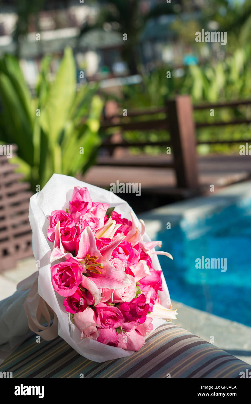 Thème de couleur rose bouquet de roses et d'autres sur la plate-forme de soleil, bleu piscine et jardin verdoyant arrière-plan. Banque D'Images