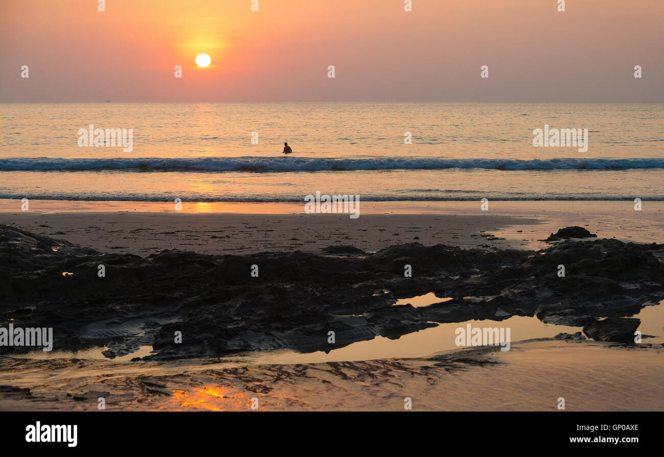 Seascape sunset beach, vue sur mer et silhouette homme seul avec rock sur le premier plan. Banque D'Images