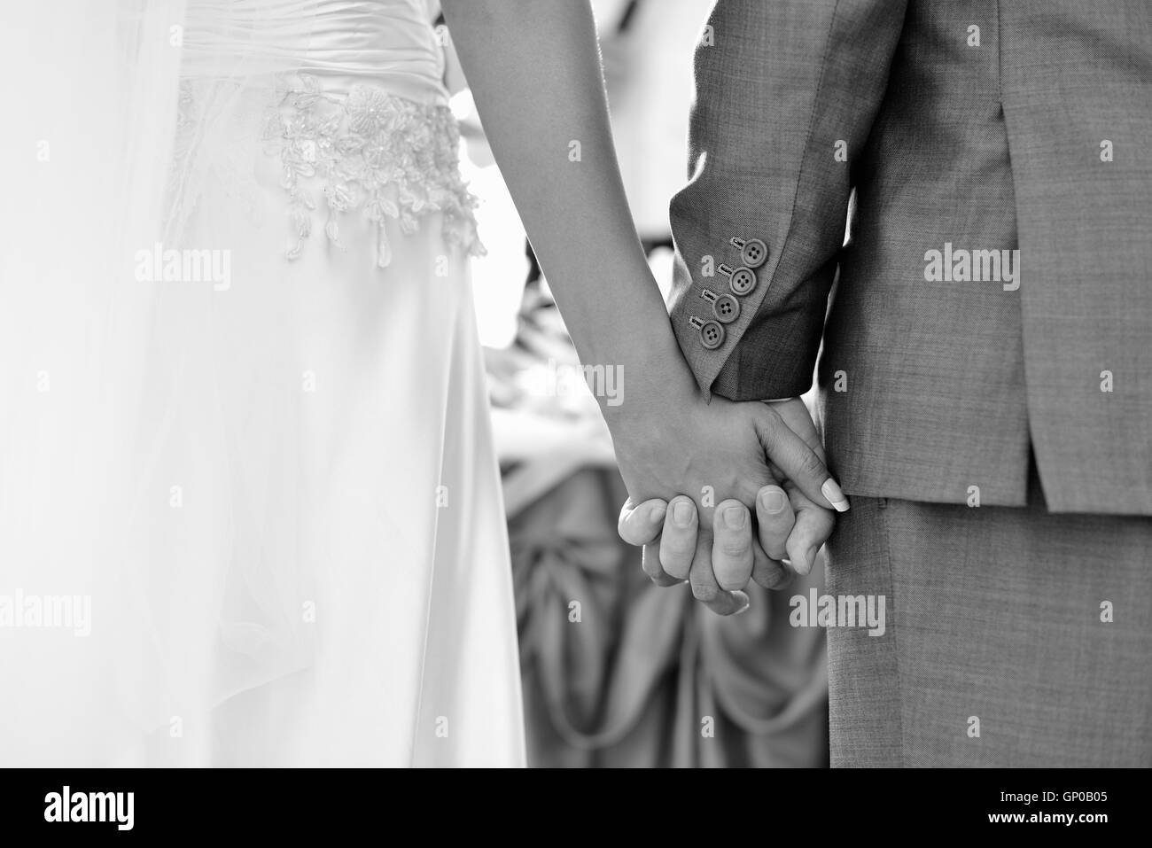 Groom holding promise en mariage à l'extérieur, main tenant les mains des jeunes mariés. Banque D'Images