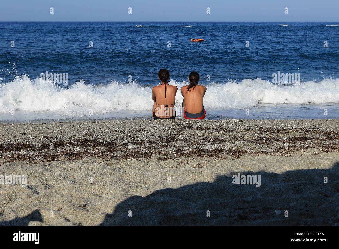 Un homme et une femme s'est assise dans le sable sur une plage dans la région de Pélion, Grèce. Banque D'Images