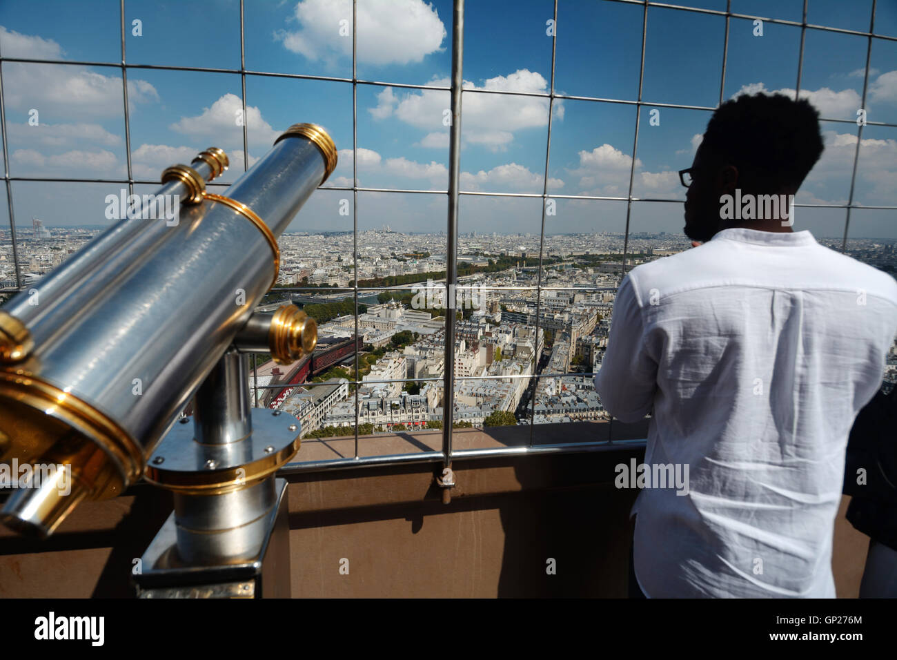 France, Paris, une personne noire en tournant le dos à l'appareil photo l'affichage de Paris Tour Eiffel debout à côté d'un télescope de monnaie Banque D'Images