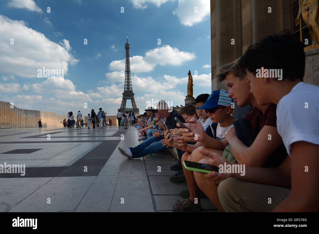 France, Paris les jeunes gens assis sur les marches d'affilée et en regardant son mobile avec Tower-Tour Eiffel dans l'arrière-plan Banque D'Images
