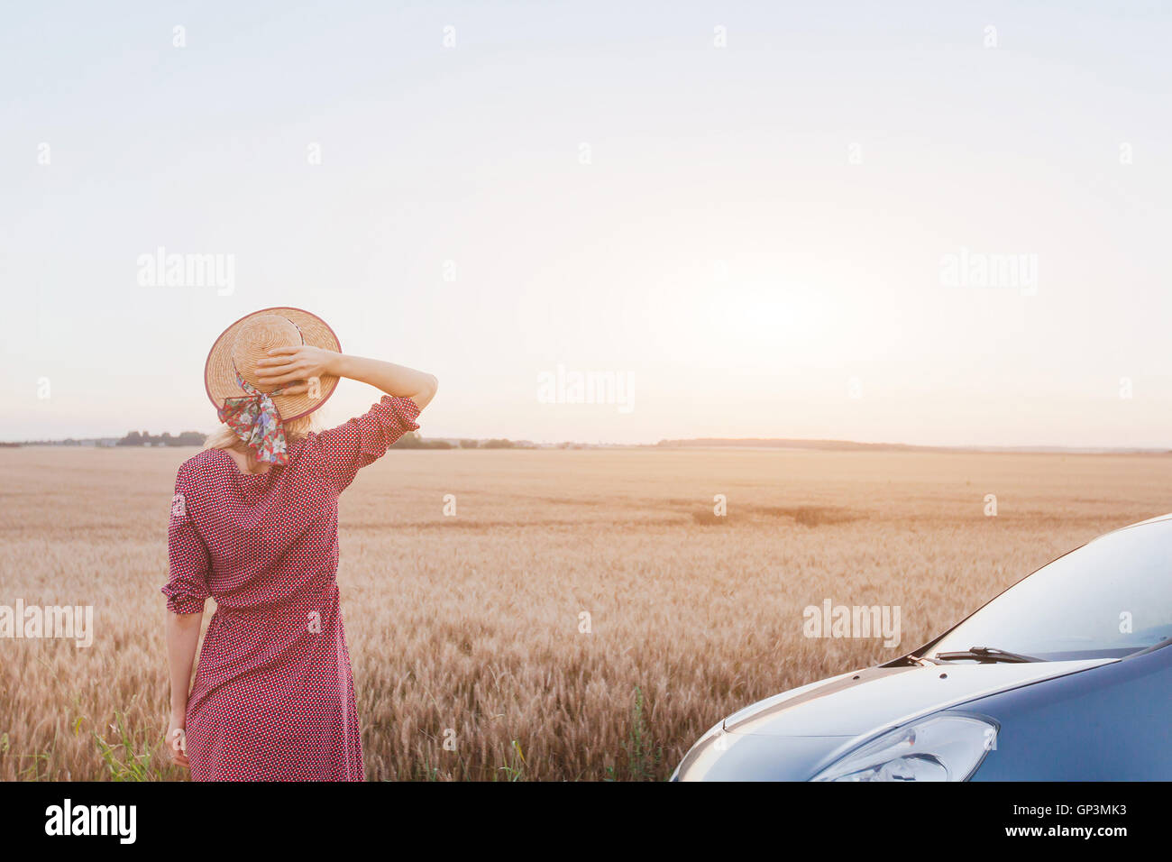 Voyager en voiture, été roadtrip, woman enjoying coucher du soleil dans les champs près de la route Banque D'Images