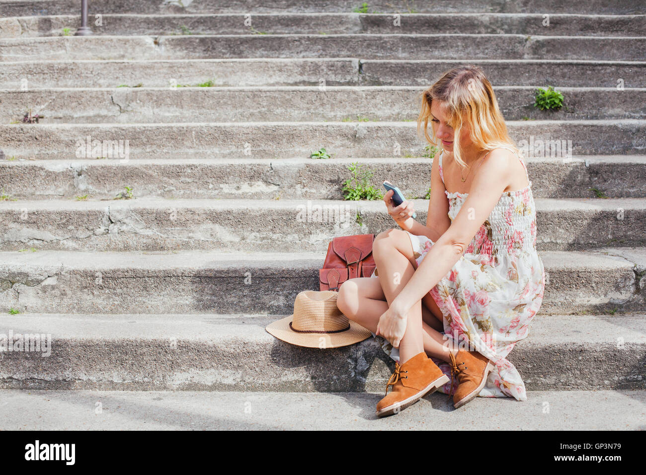 Texting on smartphone, mobile app à l'aide d'une femme, assise sur les escaliers, réseau social Banque D'Images