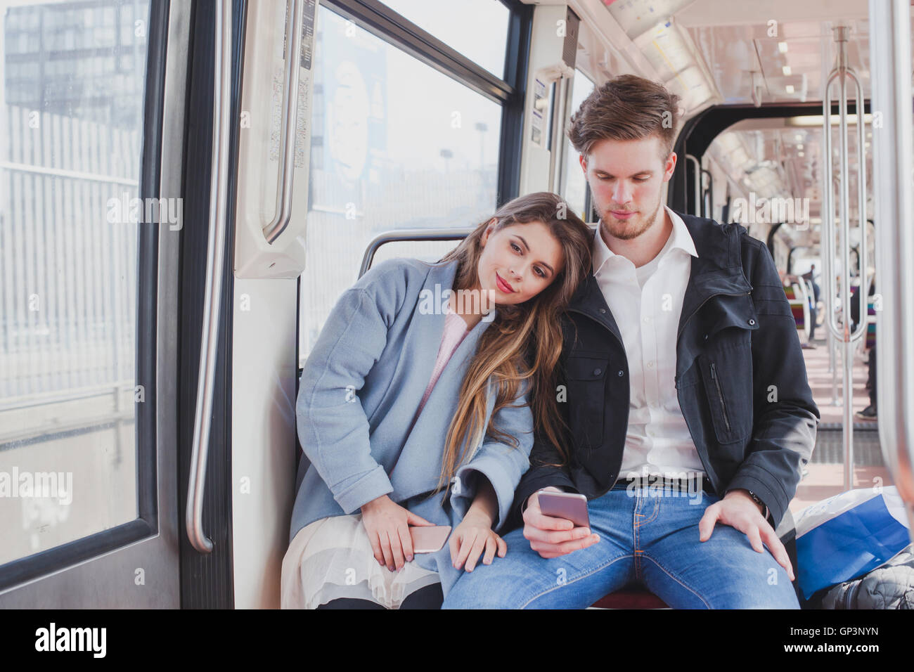 Couple dans le métro, les jeunes banlieusards siégeant ensemble Banque D'Images