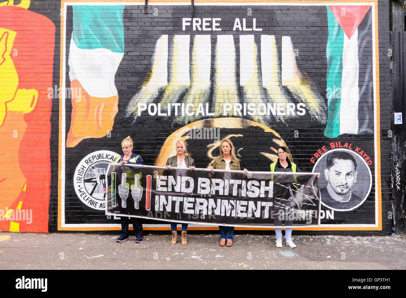 Quatre femmes tenir une banderole appelant à la fin de l'Internement britannique, tandis que debout à côté de la fresque IRPWA appelant à la version de tous les prisonniers politiques à l'International Peace Wall, Falls Road, Belfast. Banque D'Images