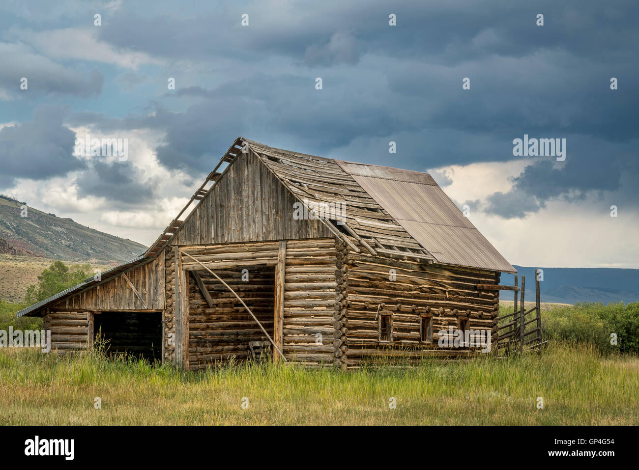 Ancienne, rustique, log barn dans les Montagnes Rocheuses du Colorado avec un ciel d'orage Banque D'Images