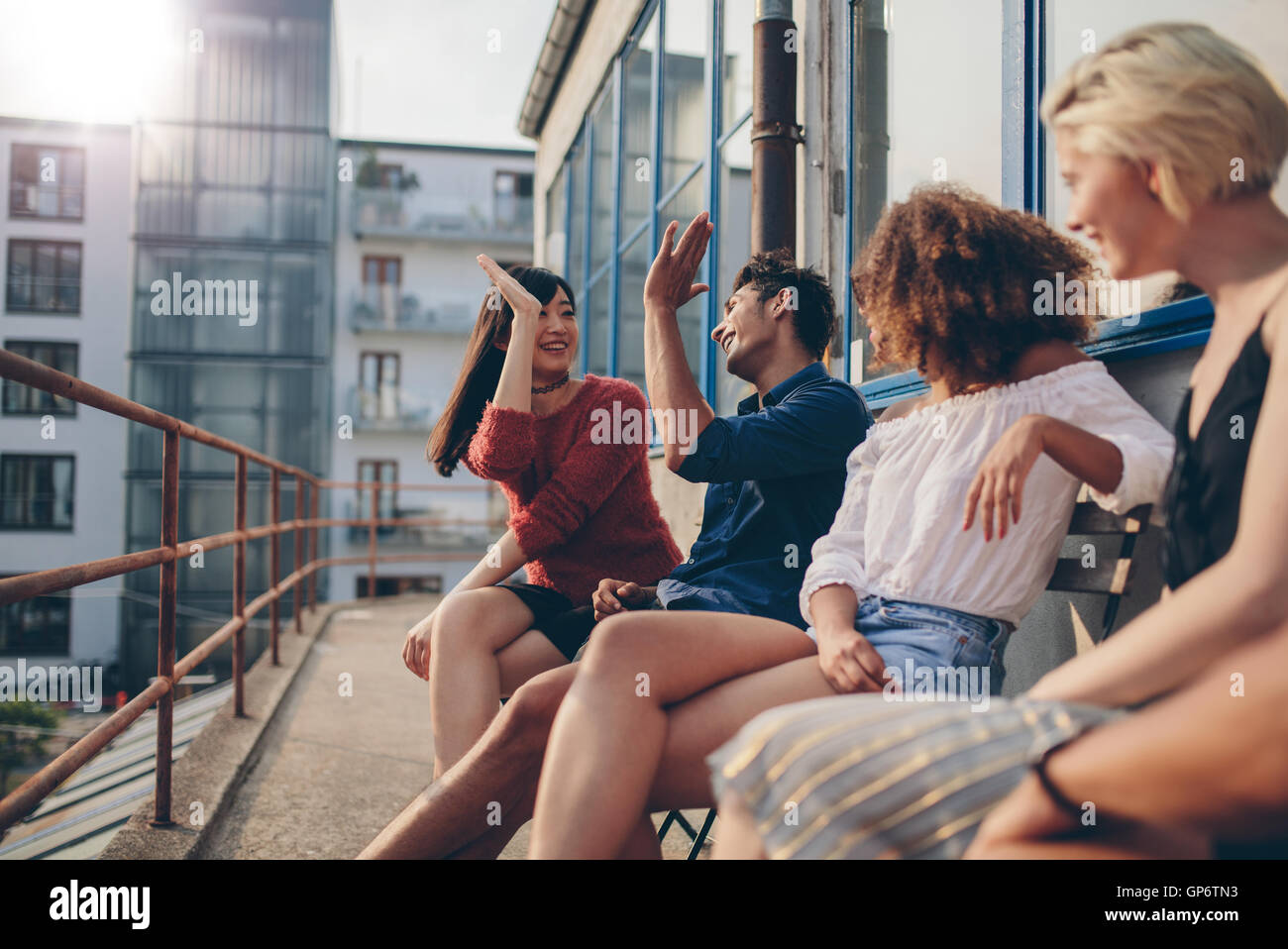 Groupe multiracial d'amis s'amusant en balcon et offrant un rapport 5. Les jeunes bénéficiant d'une terrasse. Banque D'Images