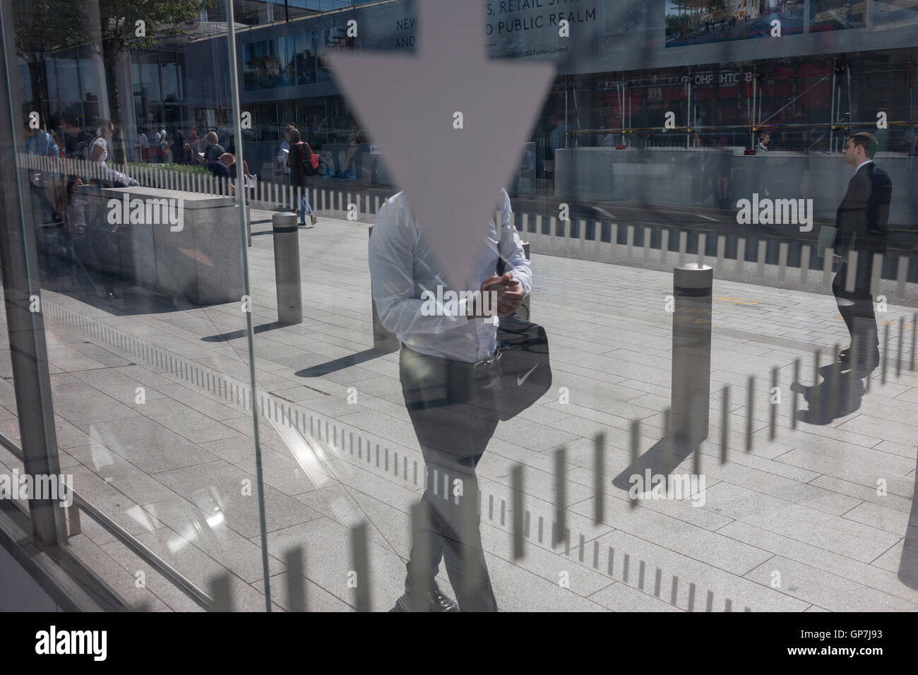 Une flèche vers le bas et l'homme sans tête en passant devant les marques de fenêtre à Southwark, Londres du sud. Banque D'Images