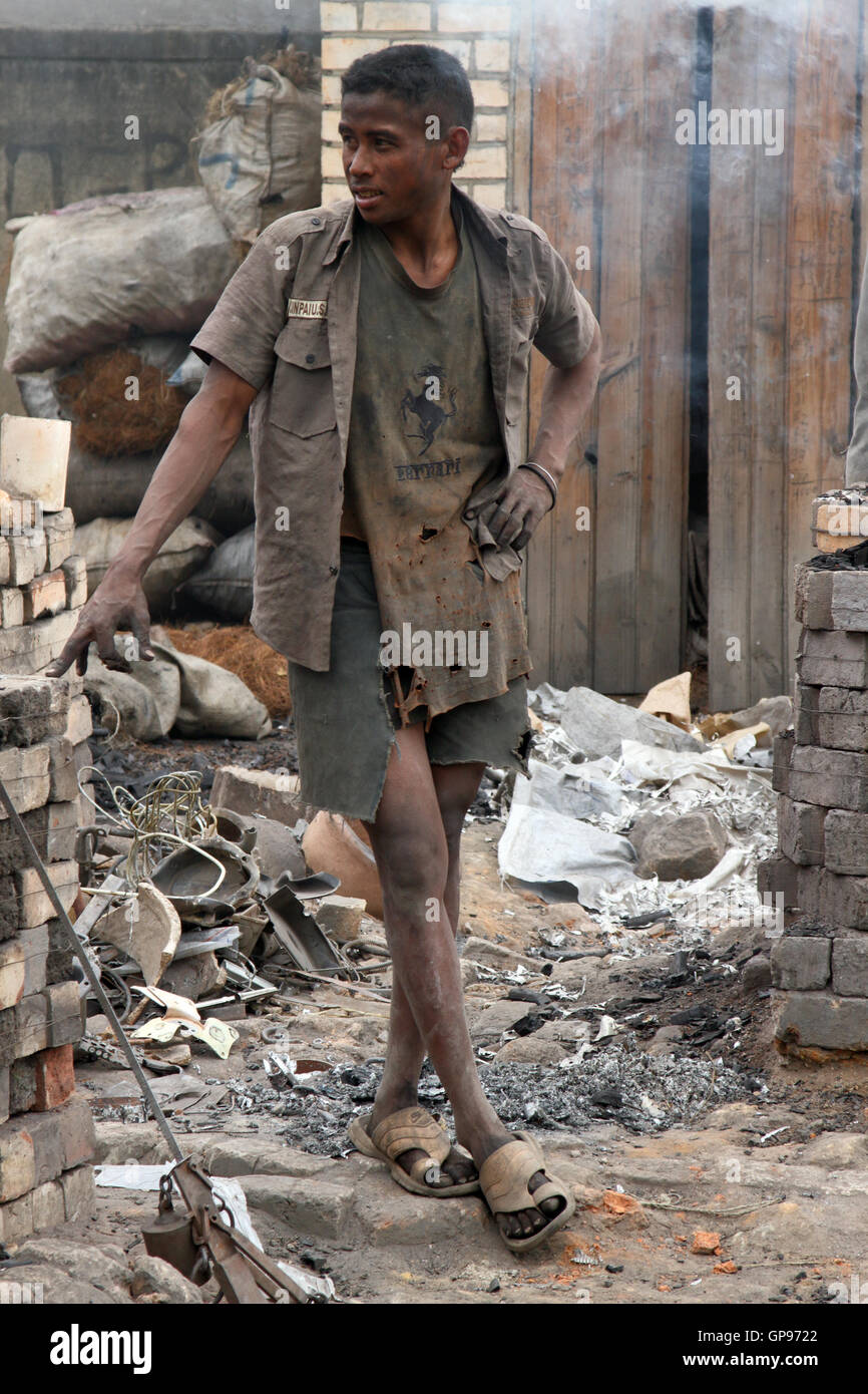 Jeune homme prendre une pause pour le recyclage des boîtes de conserve dans des pots et casseroles en usine de recyclage de l'aluminium dans Ambatolampy, Madagascar Banque D'Images