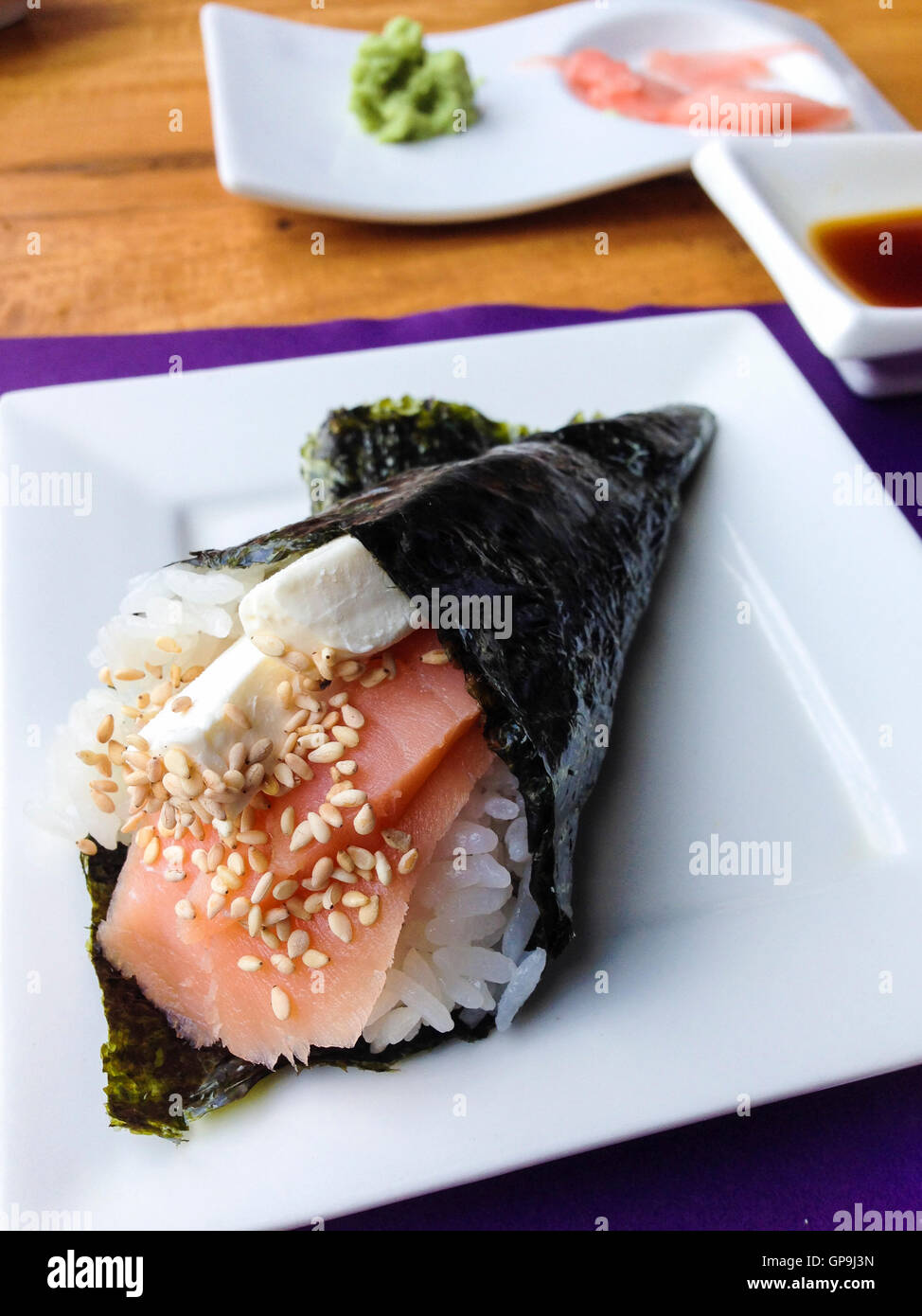 Rouleau de sushi rempli de riz, saumon cru, fromage à la crème et les graines de sésame en face de gingembre avec le wasabi et la sauce soja. Japane Banque D'Images