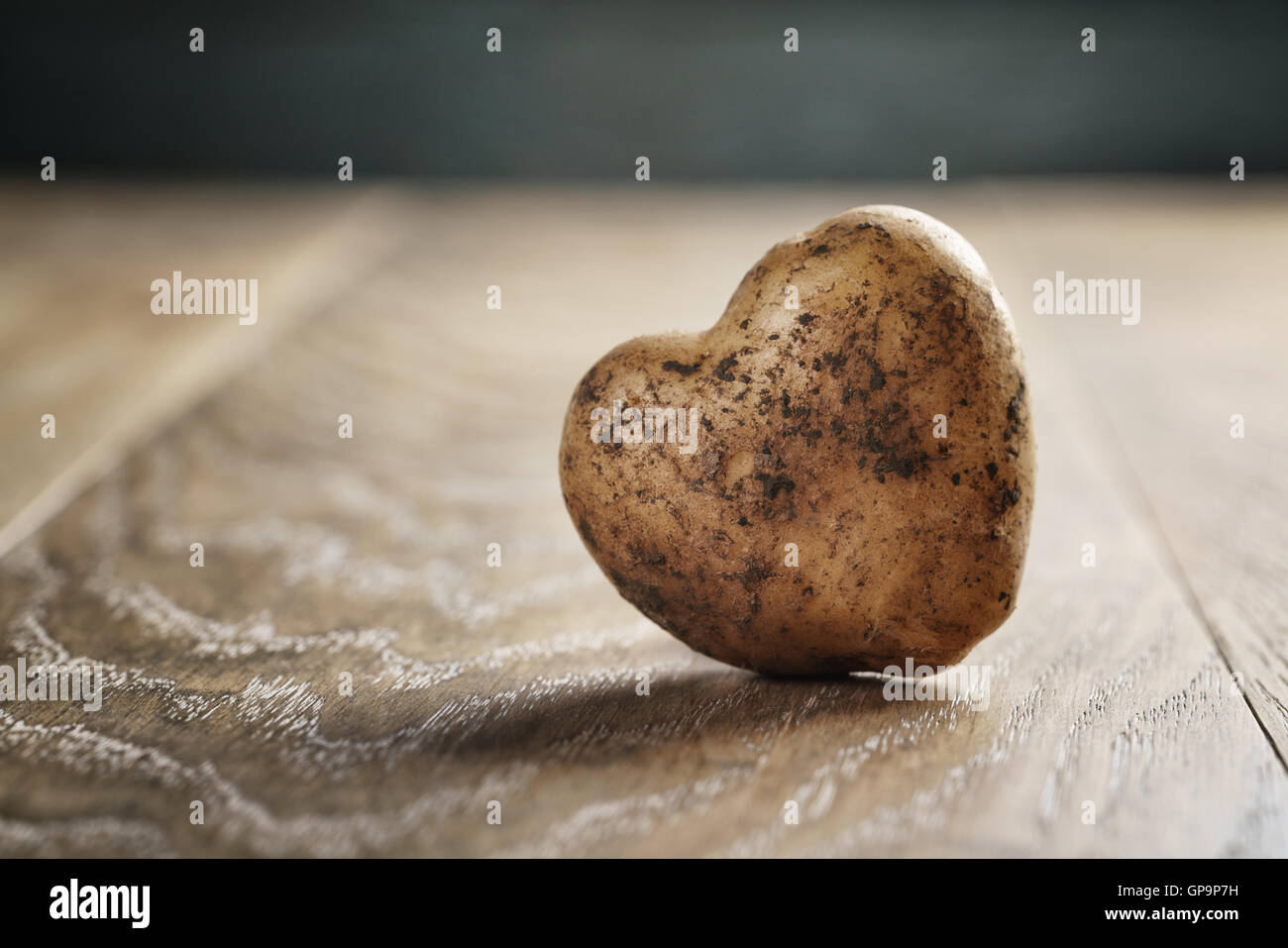 La pomme de terre en forme de coeur sur table en chêne Banque D'Images