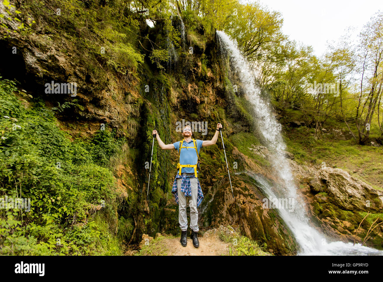 Jeune randonneur est arrêté près d'une cascade de montagne pour se reposer Banque D'Images